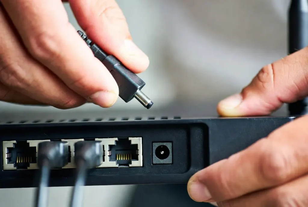 A technician restarts a router and modem to show how to fix packet loss windows 11 during home network recovery.